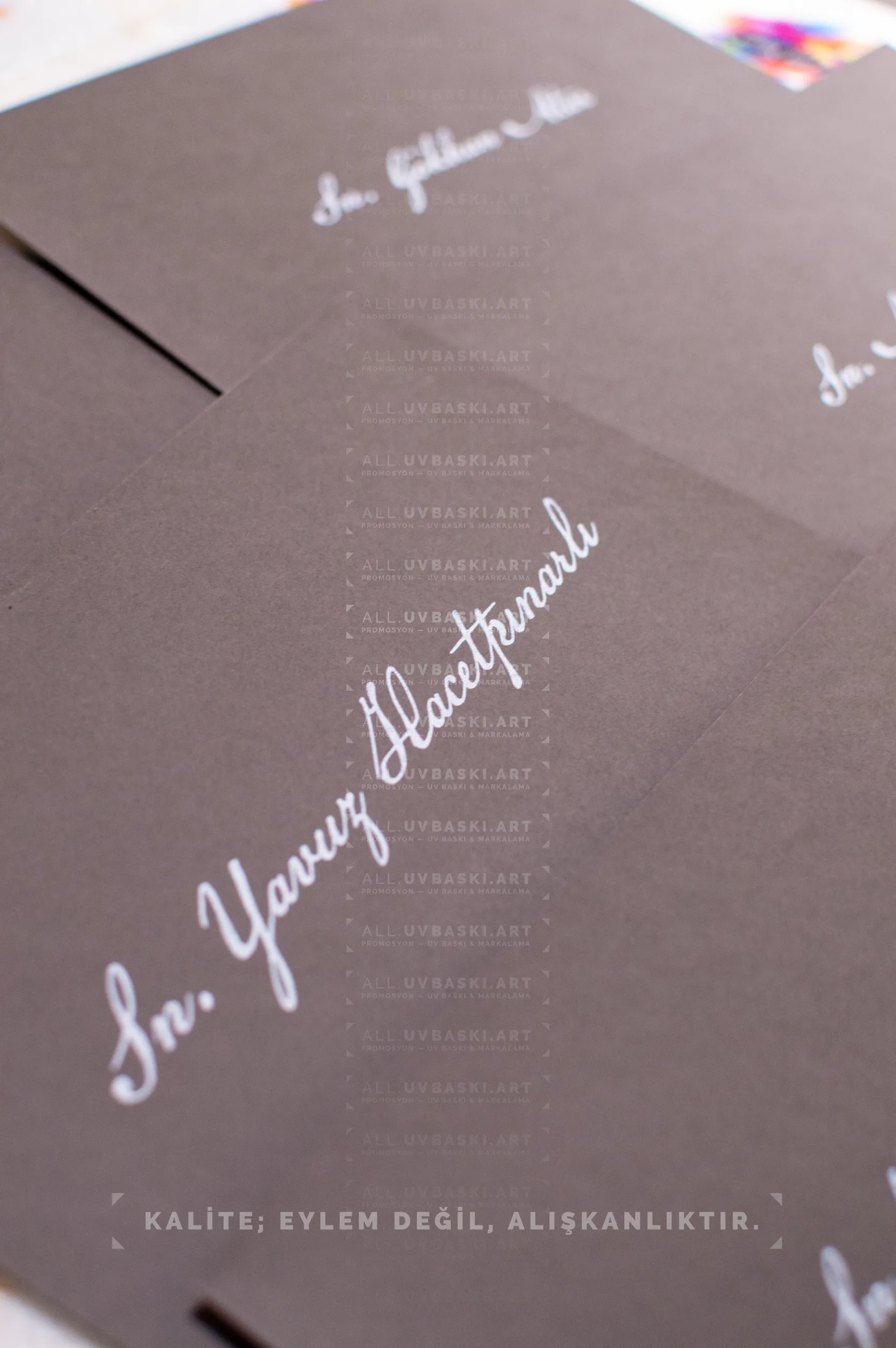 Siyah zarf &uuml;zerine beyaz yazı kaligrafi ile yazılmış davetli ismi.