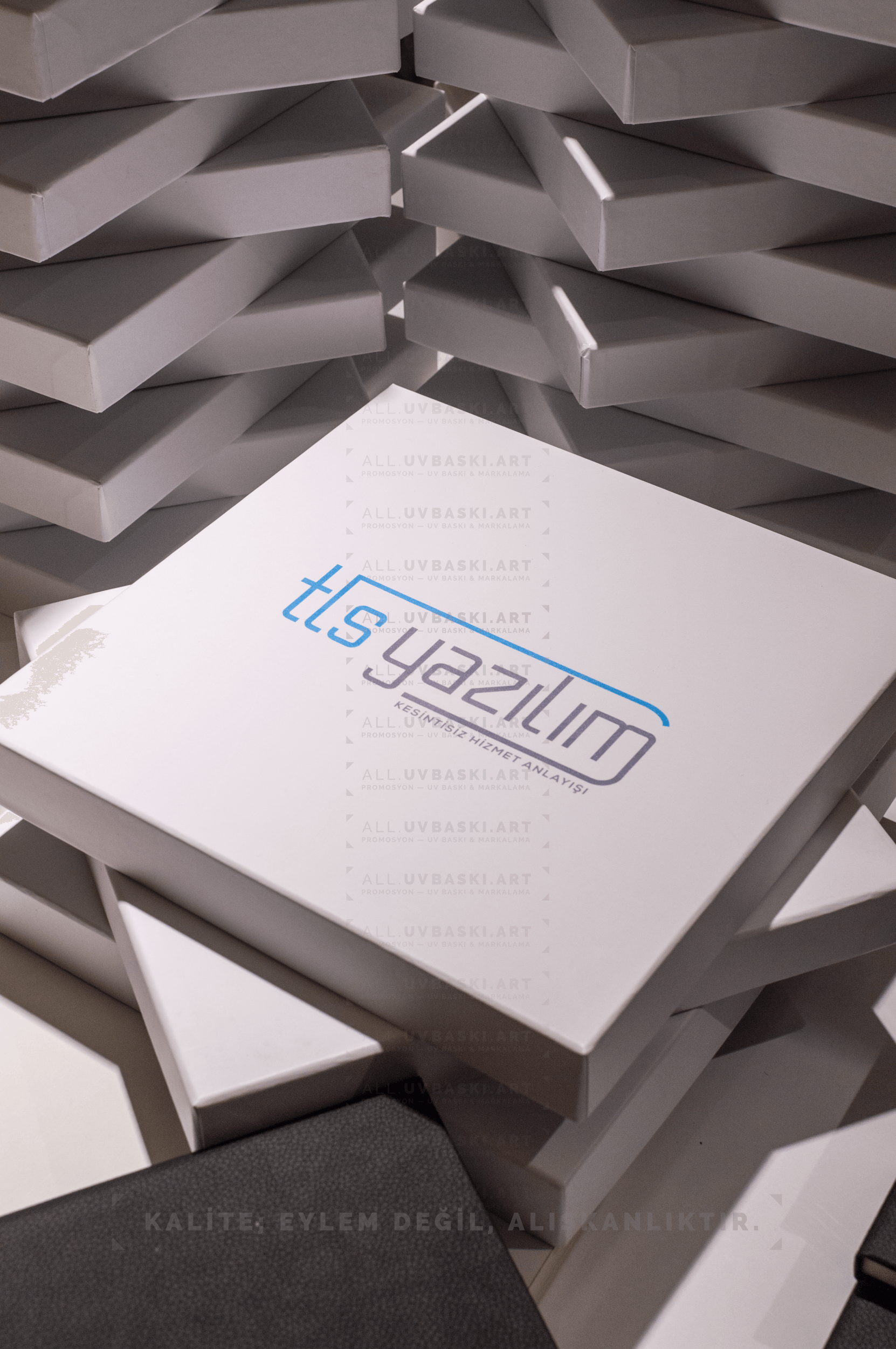 Beyaz kutu kapağı üzerine koyu gri renkte logo ve metin UV baskısı.