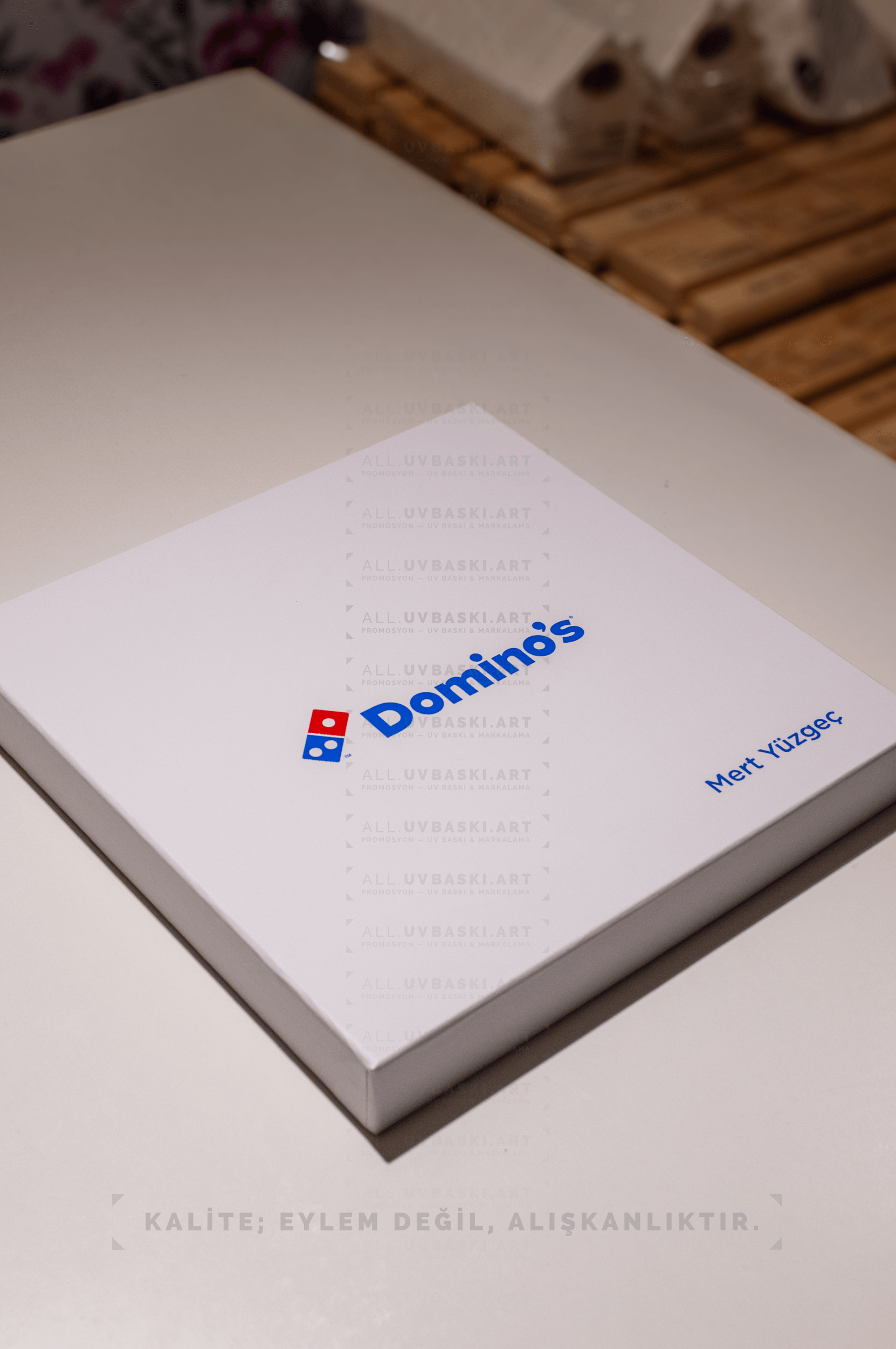 Beyaz kutu kapağı üzerine mavi tonlarda Domino's logosu ve kişiye özel isim UV baskısı.