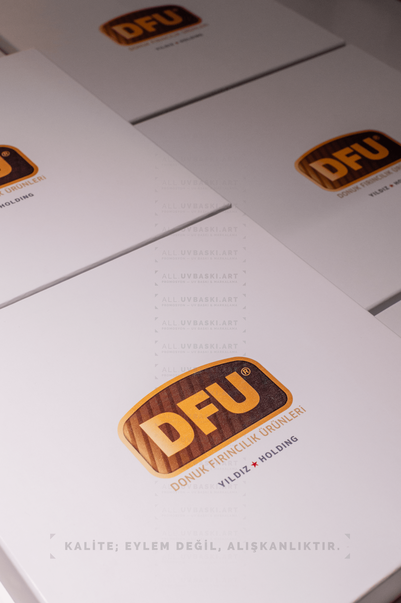 Beyaz kutu kapağı üzerine turuncu ve kahverengi tonlarında DFU logosu UV baskısı.