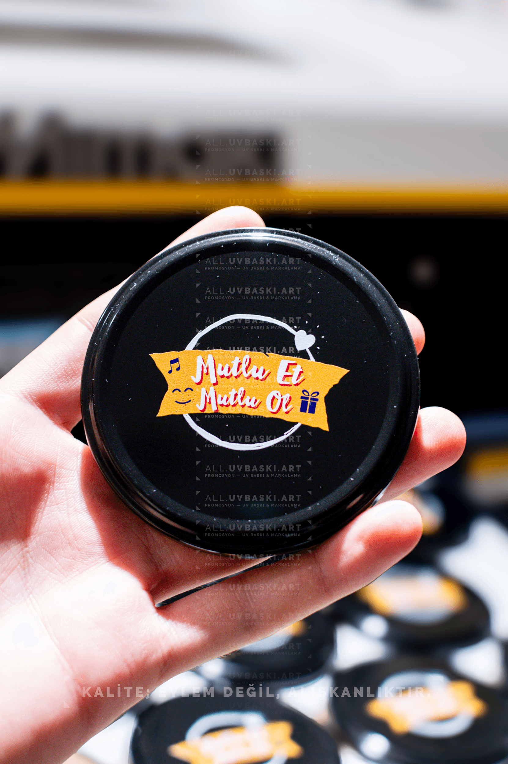 Siyah kavanoz kapağı üzerine Ülker Mutlu et, mutlu ol motto logosu, UV baskı örneği.