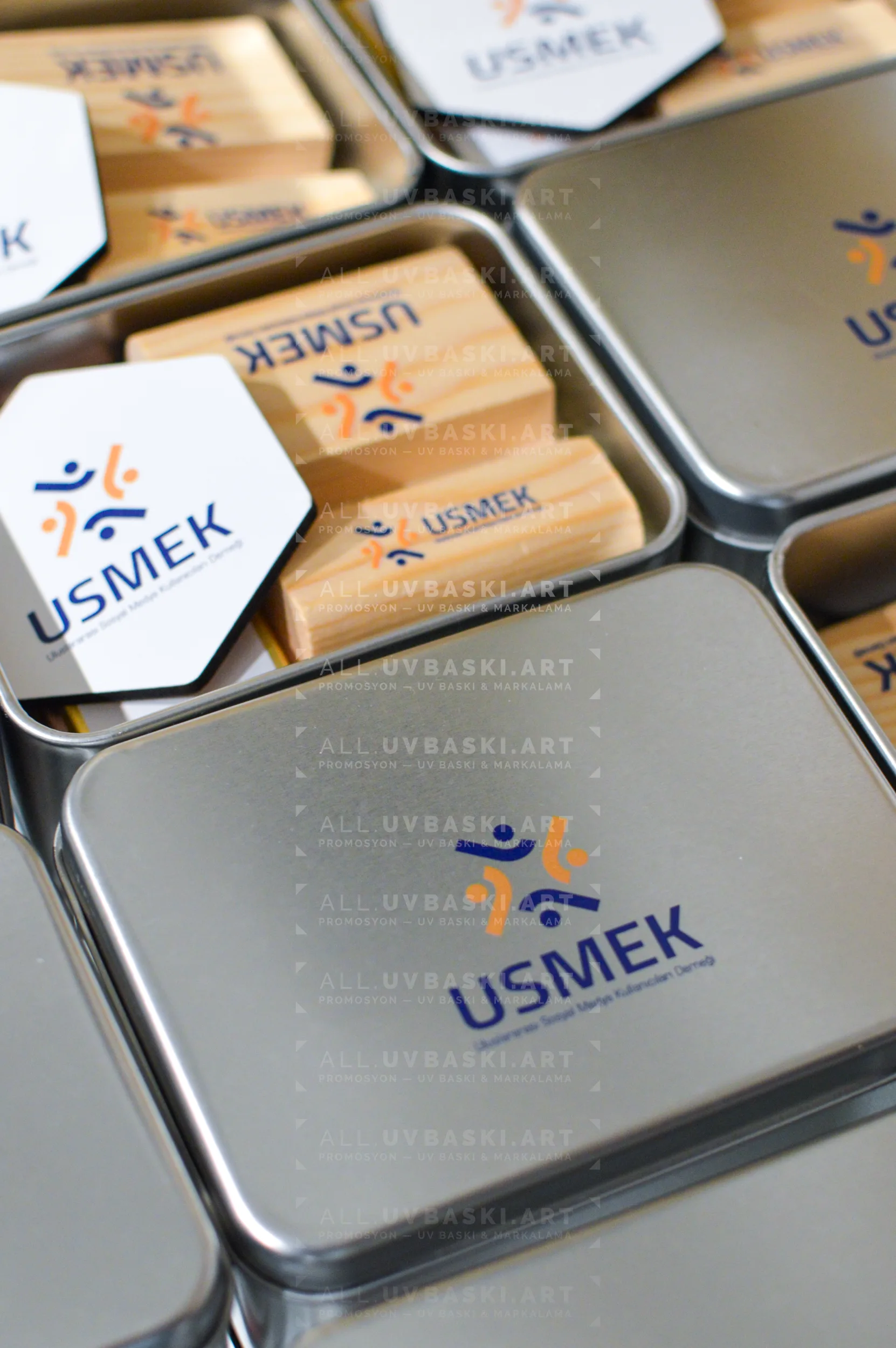 Mavi/gri teknoloji firması logolu, UV baskılı metal kurumsal hediye seti kutusu; içinde kahve, açacak, çikolata, magnet, telefon standı.