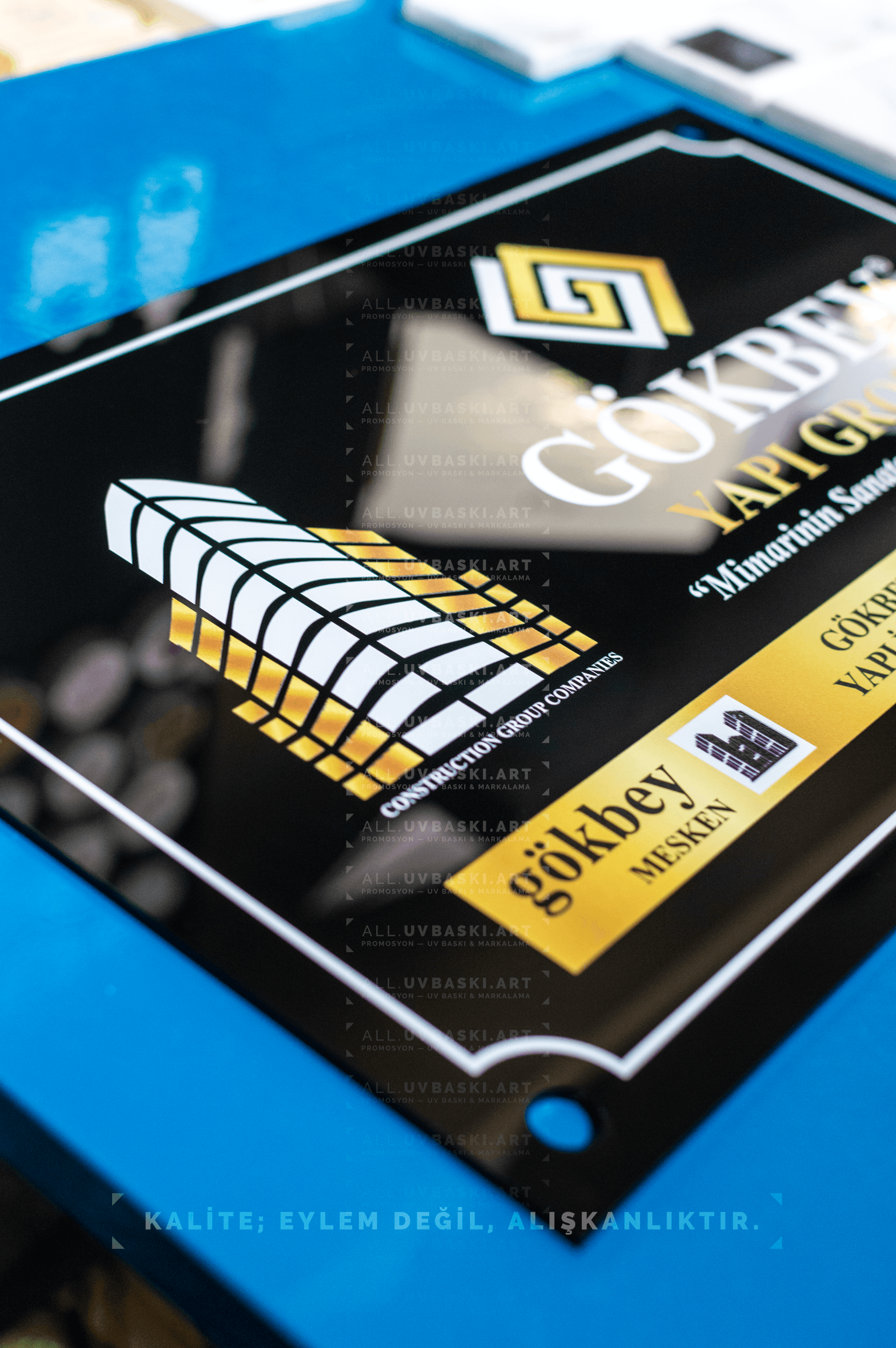 Siyah pleksi üzerine UV baskılı, beyaz ve altın renkli şirket ismi tabelası